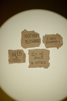 Cardboard signs with messages about job loss and economic crisis, emphasizing unemployment issues.