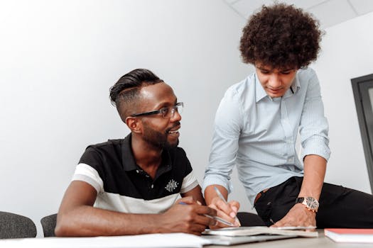 Two coworkers collaborating at a desk, emphasizing teamwork and idea sharing.