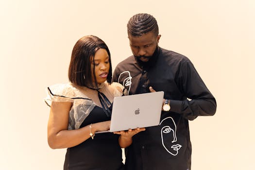 Two professionals working together on a laptop, showcasing teamwork in a modern office setting.